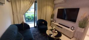 uma sala de estar com 2 sofás azuis e uma televisão de ecrã plano em The Lennox Suite Room em Acra