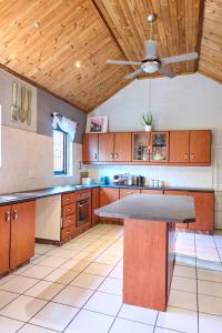 cocina grande con armarios de madera y ventilador de techo en Alakhe Self-Catering Accomodation Twin Bedroom, en Oudtshoorn