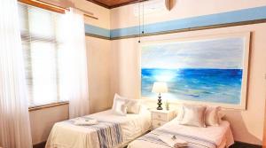 two beds in a room with a painting on the wall at Alakhe Self-Catering Accomodation Twin Bedroom in Oudtshoorn