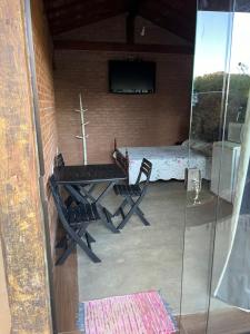 a patio with a table and chairs and a bed at Chalé Póca in Conceição da Ibitipoca