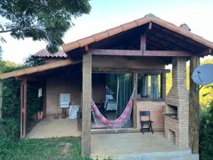 a house with a porch with a hammock on it at Chalé Póca in Conceição da Ibitipoca