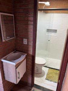 a bathroom with a toilet and a glass shower at Chalé Póca in Conceição da Ibitipoca