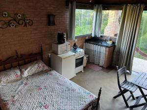 a bedroom with a bed and a stove and window at Chalé Póca in Conceição da Ibitipoca