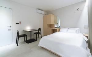 ein weißes Schlafzimmer mit einem Bett und einem Tisch in der Unterkunft Aank Hotel Incheon Wolgot in Siheung