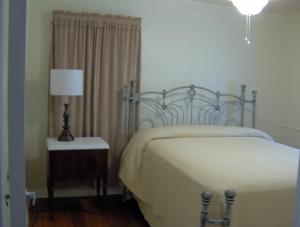 ein Schlafzimmer mit einem Bett und einer Lampe auf einem Tisch in der Unterkunft Mid-Century Modern meets Cajun Creole in Baton Rouge