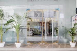 a store front with a golden door and palm trees at Hotel AMBE INN By Ambience Delhi IGI Airport in New Delhi
