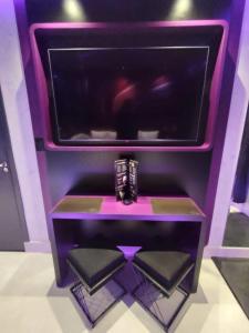 Un puesto púrpura con una TV encima. en Prestige Motel 6, en Sorocaba