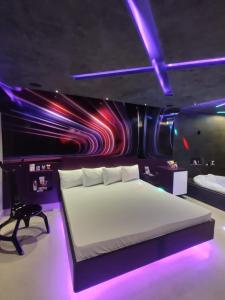 Prestige Motel 6 في سوروكابا: غرفة نوم مع سرير كبير مع أضواء أرجوانية