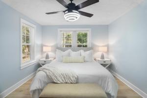 a white bedroom with a bed and two windows at Forest Hills Manor in Augusta