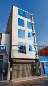 un edificio blanco alto con una puerta delante en Samaná Hs en Tacna