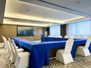 a conference room with a blue table and white chairs at Tianjin Polar Ocean Hotel in Binhai