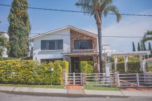 a white house with a palm tree and a fence at Casa Vacacional, Lomas Cocoyoc in Texcalpan
