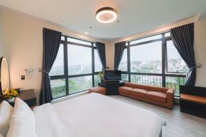 a bedroom with a large bed and large windows at Greenview Hotel DaLat in Da Lat