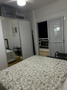 een slaapkamer met een bed en een kamer met een raam bij Apto no Tombo in Guarujá