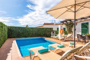 - une piscine avec des chaises et un parasol dans l'établissement Villa Nuria Bosch, à Cala'n Bosch