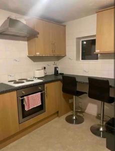 a kitchen with a stove and two chairs in it at Stevenage Studios - Master Suite in Stevenage