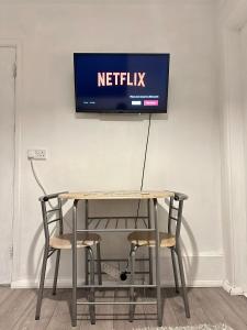 a table with two chairs and a television on a wall at Stevenage Studios - Master Suite in Stevenage