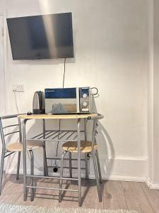a table with a microwave and a computer on it at Stevenage Studios - Master Suite in Stevenage