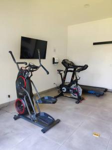 a room with three exercise bikes and a flat screen tv at Hogar verde in Alajuela