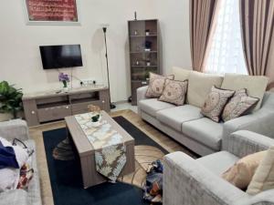 ein Wohnzimmer mit 2 Sofas und einem Couchtisch in der Unterkunft Homestay Astana Bonda Ibu in Merlimau