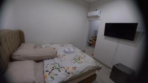Habitación pequeña con cama y TV de pantalla plana. en BELLA NINE EXCLUSIVE HOMESTAY en Sukoharjo