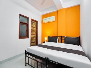 um quarto com uma cama com uma parede laranja em OYO Hotel Dev Palace em Nova Deli