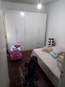 a bedroom with a bed and a pink suitcase and a chair at Condomínio Verdes Mares in Aracaju