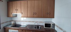 a kitchen with wooden cabinets and a sink and a microwave at ABUELA MARIA in Pasarón