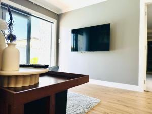 a living room with a table and a tv on a wall at Business or Holiday 4 bedrooms house in Hamilton with pool and spa in Hamilton