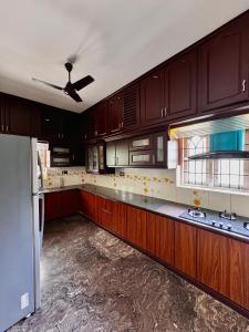 a kitchen with wooden cabinets and a ceiling fan at Chilanka Place HOME AWAY FROM HOME - Ernakulam- Kerala in Cochin