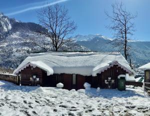 une cabine recouverte de neige avec de la neige sur le toit dans l'établissement Apple Valley Cottages Lachung, à Lachung