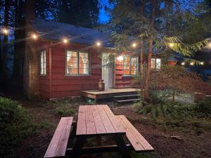 una mesa de picnic frente a una casa por la noche en Springbrook · Cozy 2BR Mt. Hood Cabin, Fireplace & Retro Kitchen, en Mount Hood Village