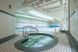 a swimming pool with a hot tub in a building at Sub-Penthouse Apartment with Jacuzzi Pool & Sauna in Vancouver