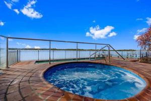 a hot tub on a patio with a view of the water at Maroochydore Riverfront Apartment in Maroochydore