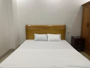 łóżko z drewnianym zagłówkiem i 2 białymi poduszkami w obiekcie 502 Sân Bay Điện Biên w mieście Dien Bien Phu
