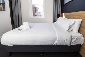 um quarto com uma cama grande com lençóis brancos e almofadas em The Albion Hotel em Wickham