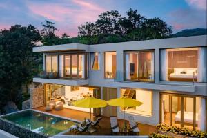 a large house with a swimming pool and yellow umbrellas at Villa Bella Vista Samui - 360 Degrees Mountain View in Taling Ngam Beach