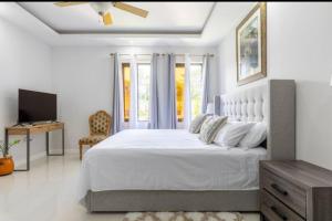 1 dormitorio blanco con 1 cama grande y TV en Luxury Palm, en Old Harbour