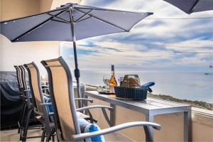 a table with an umbrella on a balcony with the ocean at Sunset Serenity On The Cliffs! in San Diego