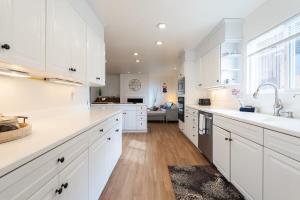 a white kitchen with white cabinets and a sink at Sunset Serenity On The Cliffs! in San Diego