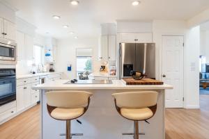 a kitchen with white cabinets and a large island with two bar stools at Sunset Serenity On The Cliffs! in San Diego