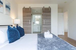 a bedroom with a large white bed with blue pillows at Sunset Serenity On The Cliffs! in San Diego