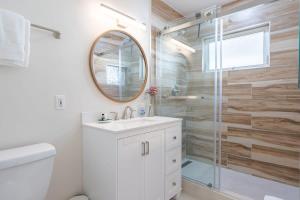 a bathroom with a sink and a shower with a mirror at Sunset Serenity On The Cliffs! in San Diego