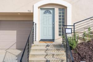 a white house with a blue door and stairs at Sunset Serenity On The Cliffs! in San Diego
