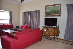 sala de estar con muebles de color rojo y TV de pantalla plana en Marina Agadir Royal Apartment, en Agadir