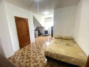 1 dormitorio con 1 cama y puerta de madera en Ballesteros Apartaments, en Puerto Ayora