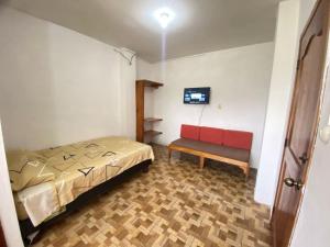 1 dormitorio con cama y banco. en Ballesteros Apartaments, en Puerto Ayora