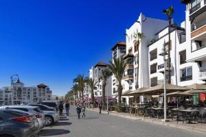 una calle con coches estacionados, edificios y palmeras en Marina Agadir Royal Apartment, en Agadir