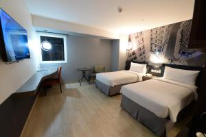 um quarto de hotel com duas camas e uma secretária em HORU HOTEL MANGGA DUA SQUARE em Jacarta