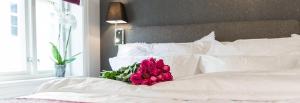 Boe Apartment Hotel في إيجرشوند: وردة حمراء جالسة فوق سرير ابيض